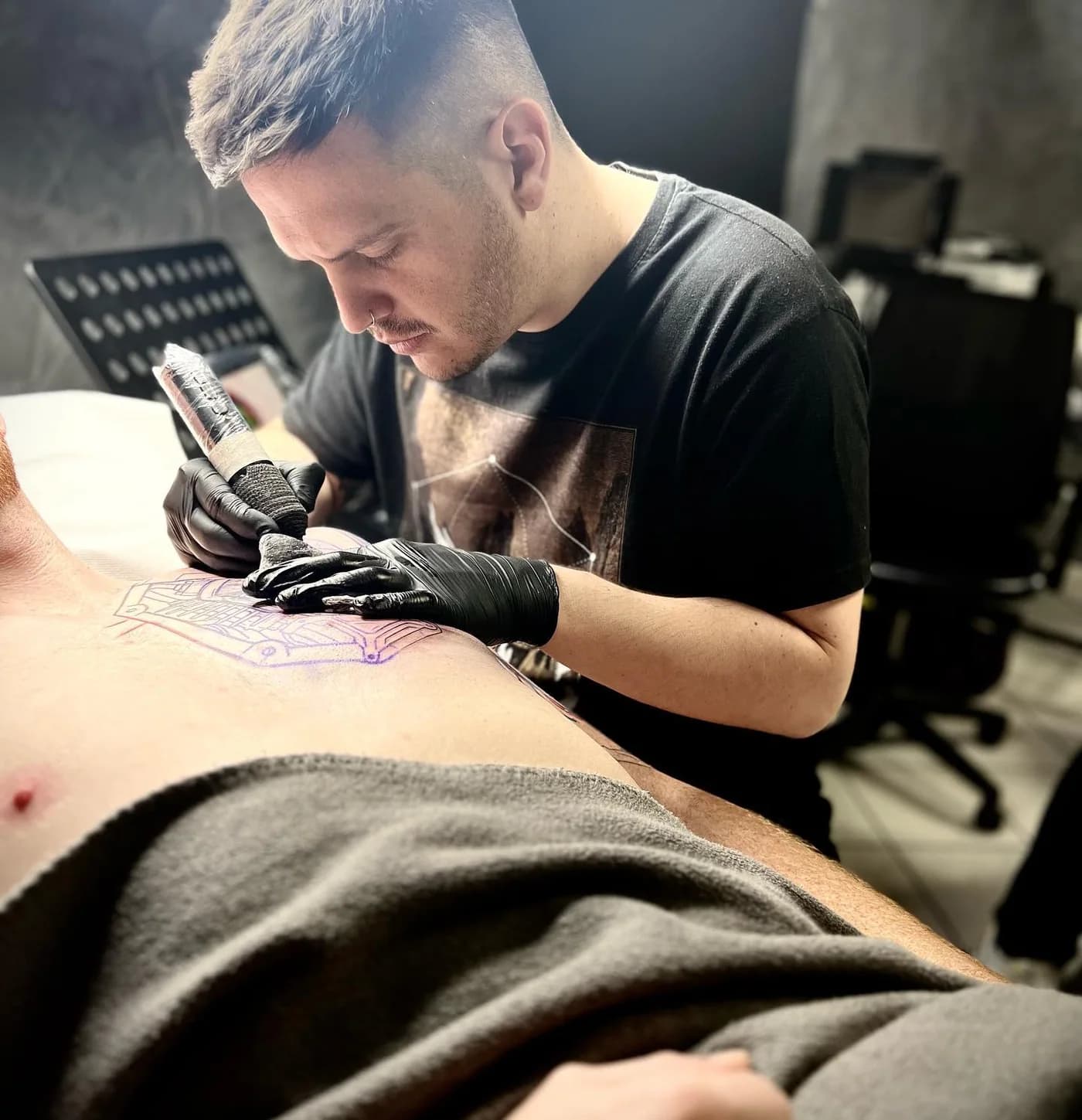 Tattoo-Artist bei der Arbeit an einem Rückenmotiv.