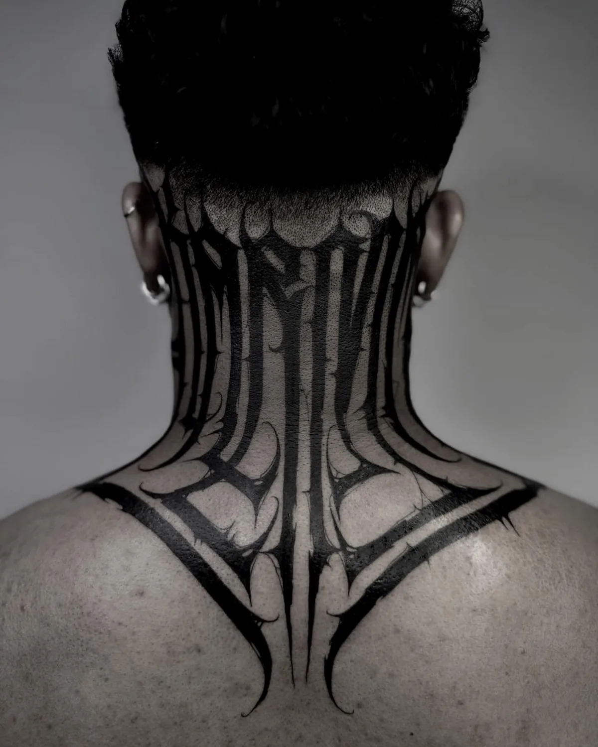 Geometrisches Blackwork-Tattoo im Nacken.